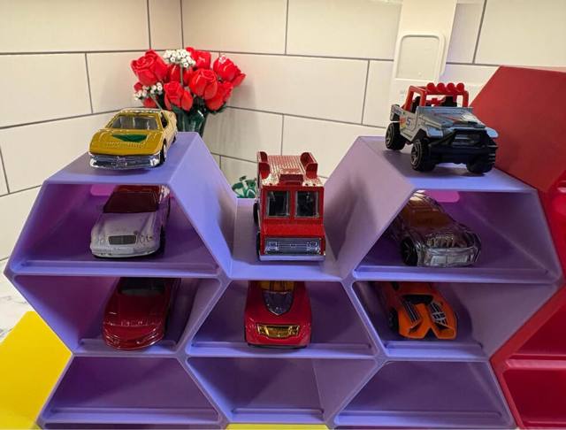 Purple toy car garage shelf filled with die-cast cars
